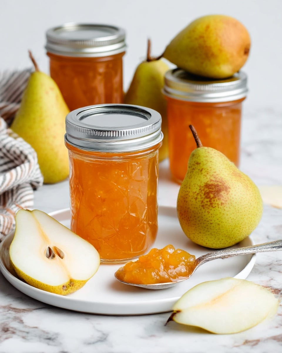 The image shows a white plate with a jar of golden-orange pear jam in the center, its surface shiny and translucent, with a silver lid on top. Surrounding the jar are three whole pears with a greenish-yellow color and brown speckles, and a couple of pear slices with light cream flesh and visible seeds. In front of the jar is a silver spoon resting on the plate, holding some chunky jam that glistens with a jelly-like texture. In the background, two more jars of the same jam are stacked on top of each other, and a striped cloth is partially visible on the left side. The surface beneath everything is a white marbled texture. photo taken with an iphone --ar 4:5 --v 7