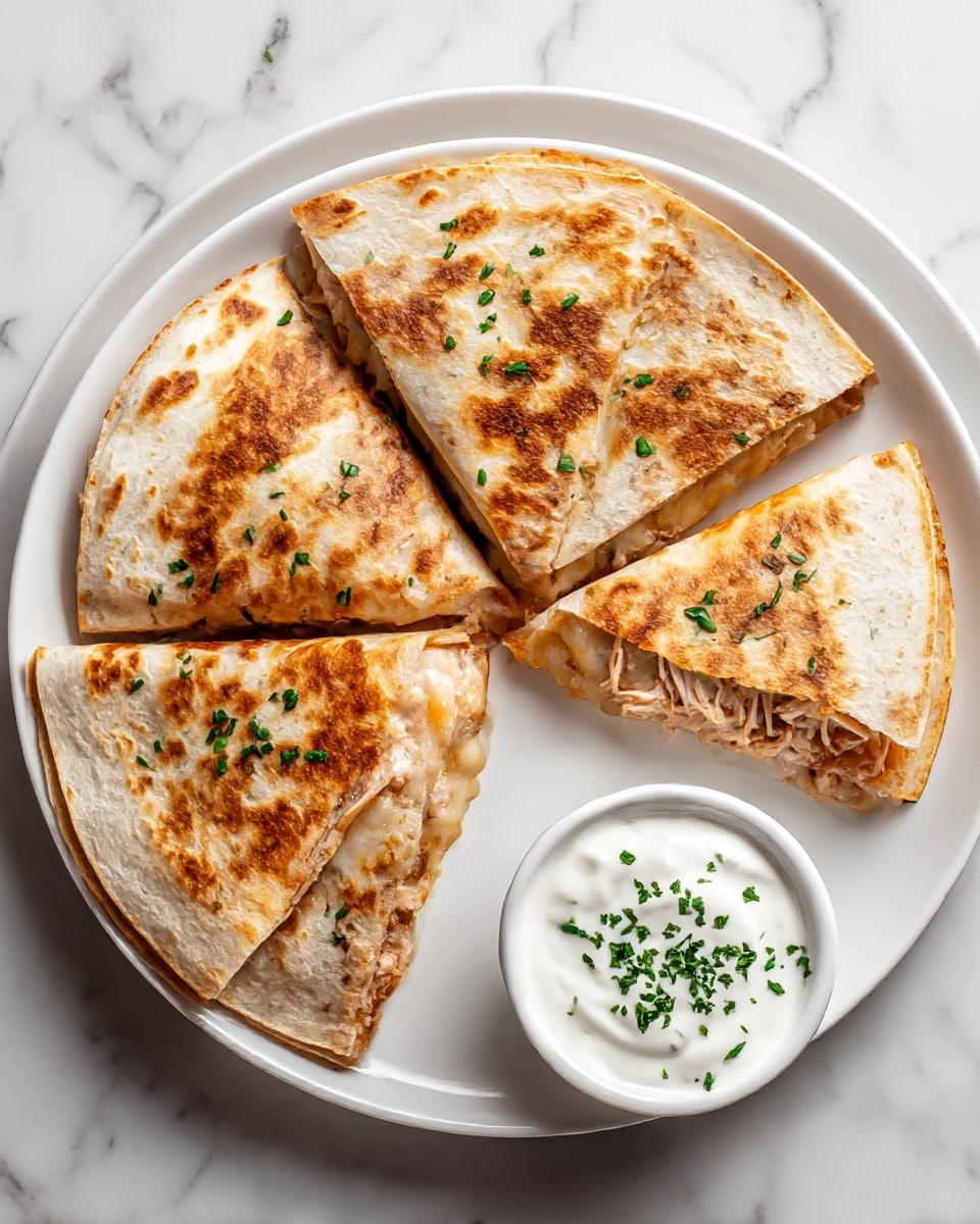 The image shows a white plate on a white marbled surface holding a quesadilla cut into four triangle pieces. Each piece has a golden-brown toasted tortilla exterior with some darker spots and is sprinkled with green herbs on top. Inside, there are visible layers of melted white cheese and shredded light brown chicken. On the same plate, there is a small white bowl filled with smooth white sour cream, also sprinkled with green herbs. Photo taken with an iphone --ar 4:5 --v 7