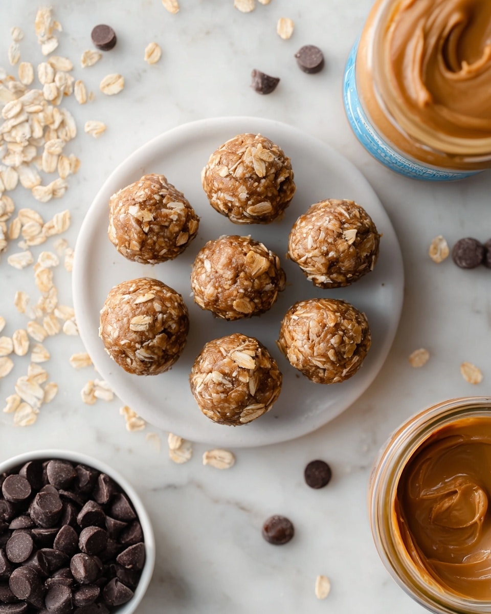 Seven small round energy bites are arranged on a small white round plate, each bite showing a light brown color mixed with visible oatmeal flakes, giving them a rough and textured look. The plate sits on a white marbled surface scattered with dry oats and dark chocolate chips around it. To the right, there is a jar of peanut butter with a smooth creamy texture seen inside, and below it, a small white bowl filled with dark chocolate chips. The overall setting is bright and clean. photo taken with an iphone --ar 4:5 --v 7
