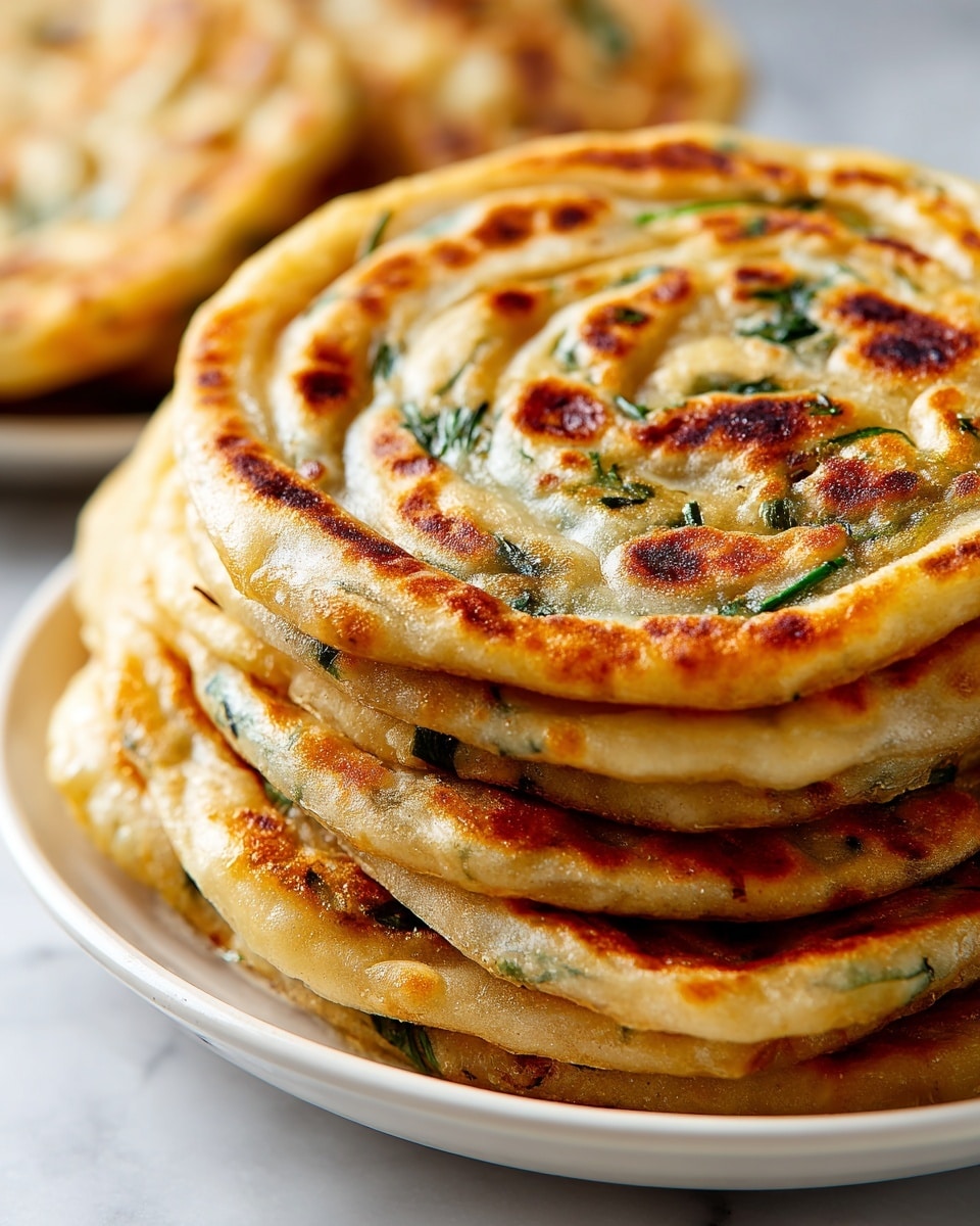 A close-up view of several golden brown spiral snacks placed in a white plate, each snack showing multiple thin layers rolled tight with visible green bits of herbs inside. The outer layers are crispy with a mix of light golden and darker browned patches, while the inner layers have a softer, slightly translucent texture. The spirals have an irregular shape with some parts puffed up and others pressed down, adding to the rustic appearance. The plate rests on a white marbled texture that softly reflects light, highlighting the warm colors of the snacks. photo taken with an iphone --ar 4:5 --v 7