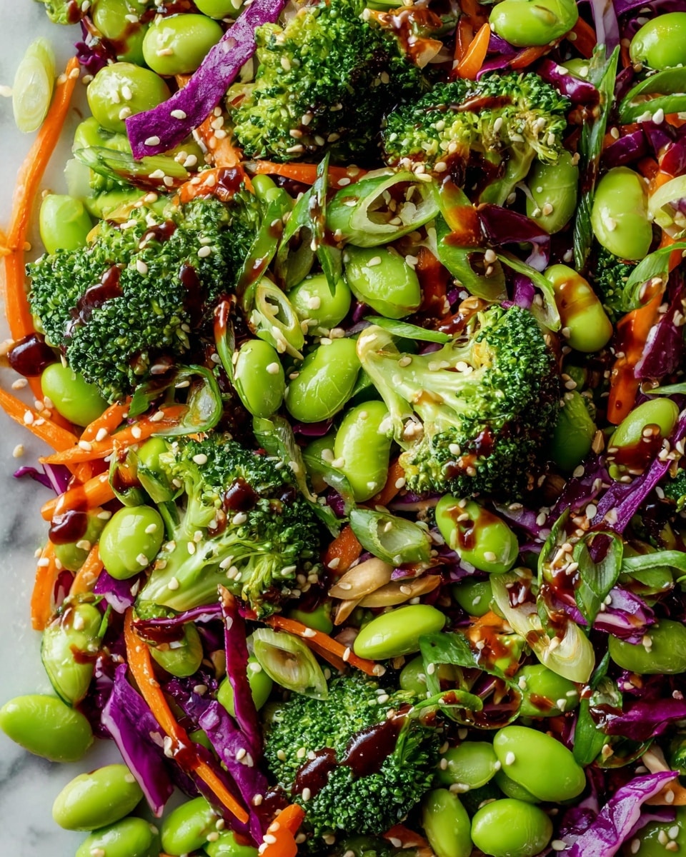 A close-up view of a colorful salad showing a mix of bright green broccoli florets and large light green edamame beans spread across the surface. Thin orange carrot strips and pieces of purple cabbage add contrast throughout the dish. Green onion slices are scattered on top, while a dark glossy dressing is drizzled over the salad, giving it a shiny texture. White sesame seeds are sprinkled over everything, adding small whitish spots to the image. The salad rests on a white marbled surface, enhancing the vivid colors of the vegetables. photo taken with an iphone --ar 4:5 --v 7