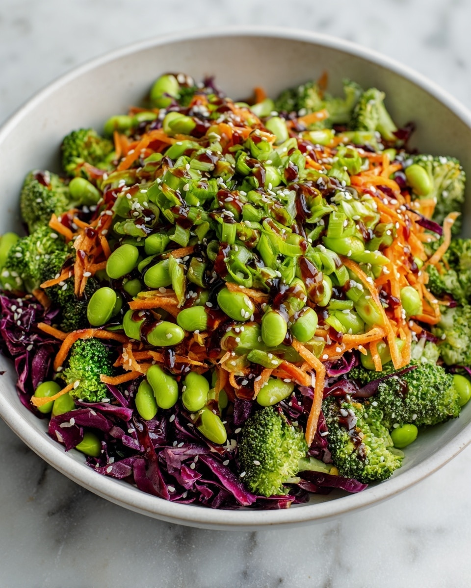 A white bowl filled with a colorful vegetable salad is shown on a white marbled surface. The salad has several layers starting with bright green broccoli florets and mixed dark purple shredded cabbage. On top are layers of light orange shredded carrots and bright green edamame beans scattered throughout. The salad is garnished with chopped green onions and white sesame seeds, with a dark, glossy sauce drizzled over the top, adding a shiny texture to the fresh vegetables. photo taken with an iphone --ar 4:5 --v 7