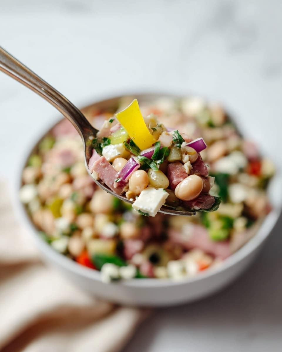 A close-up view of a fork holding a bite-sized salad portion with layers of small beige beans, light pink cubes of meat, white cheese cubes with herbs, small pieces of green leafy herbs, light purple diced onions, and a slice of yellow-green pepper on top. Below the fork, there is a white bowl filled with a colorful mixed salad containing visible layers of the same ingredients: beans, meat, cheese, peppers, onions, and greens, all mixed together with a slightly glossy texture. The scene is set on a white marbled surface with soft lighting, highlighting the fresh and vibrant colors. The focus is sharp on the fork portion, while the bowl is blurred in the background. photo taken with an iphone --ar 4:5 --v 7